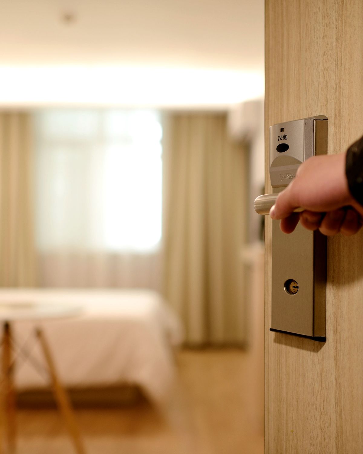 Χέρι ανοίγει την πόρτα δωματίου ξενοδοχείου